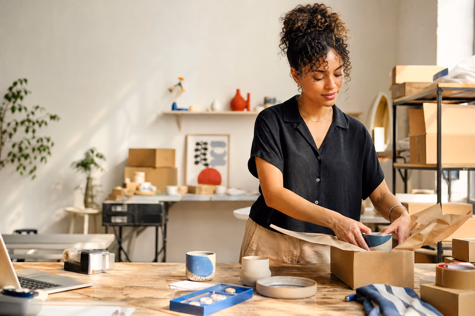 Independent ecommerce founder packing a customer order in a bright studio