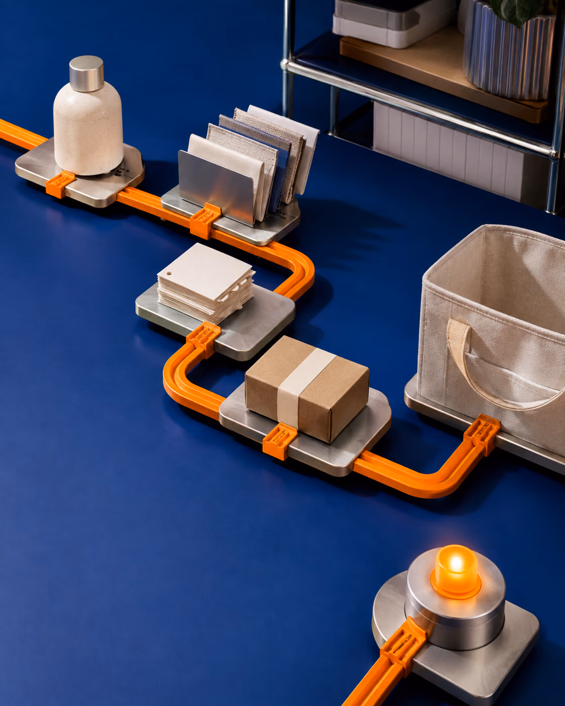 A continuous orange rail connects product samples, supplier materials, order cards, a parcel, and a tracking beacon.